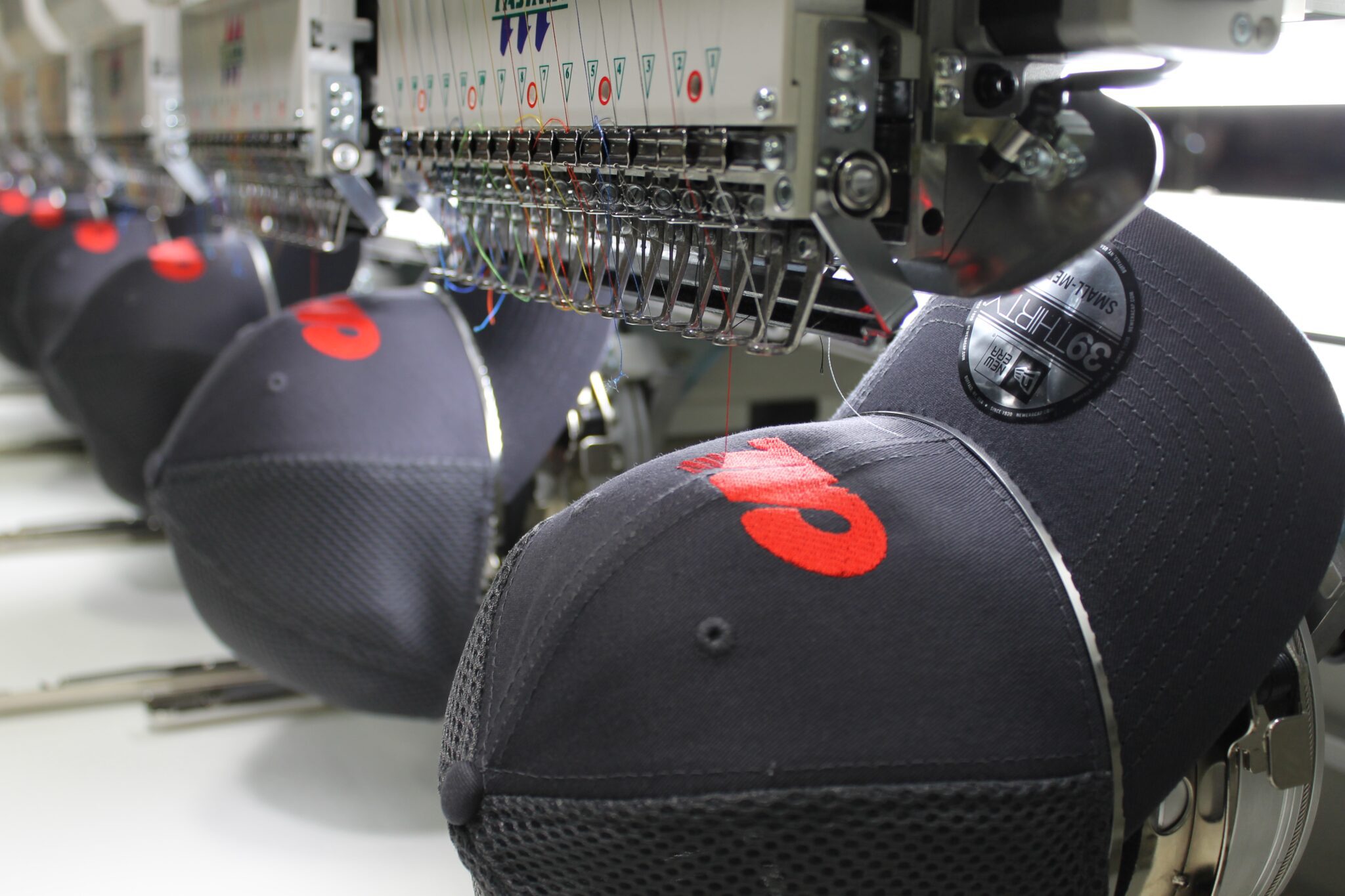Close up of employee recognition custom company logo on hats using embroidery process